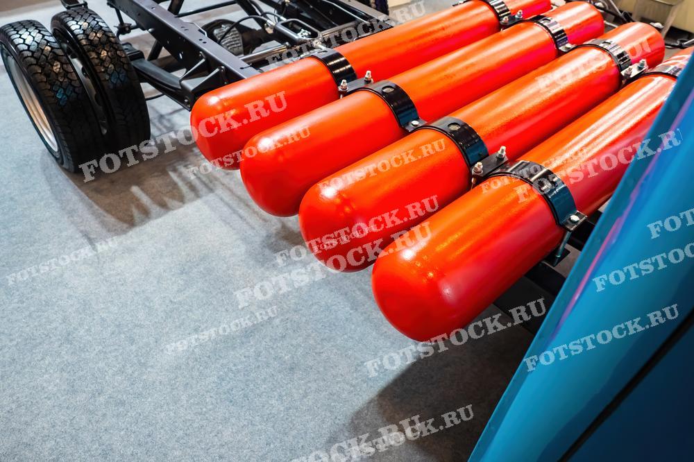 На фото изображены баллоны для сжатого природного газа, установленные на шасси автомобиля. Это иллюстрация использования газомоторного топлива в транспортных средствах для снижения вредных выбросов и повышения экологической эффективности.